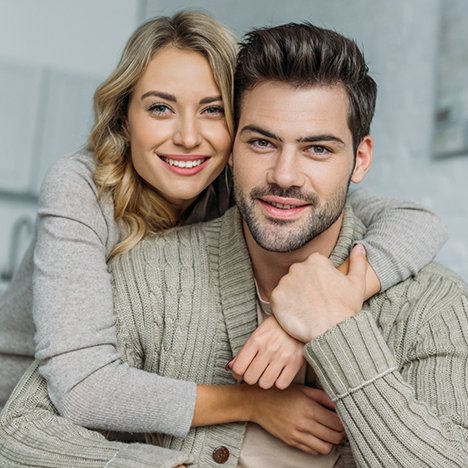 Man in sweater being hugged from behind by blonde woman