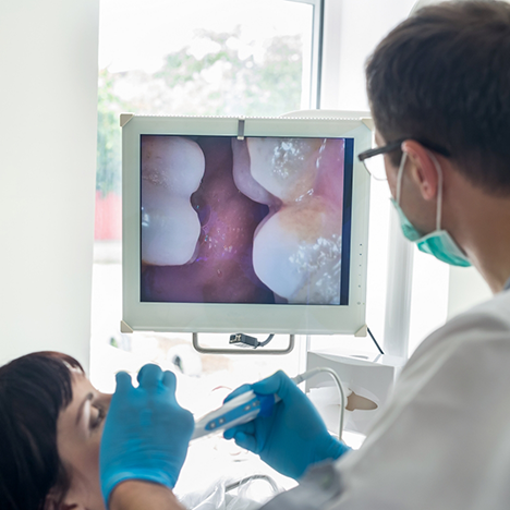 Male dental patient looking at images of teeth captured by intraoral camera