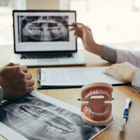 Close-up of desk with dentist pointing to X-rays