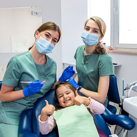 Two female dentists treating a little girl