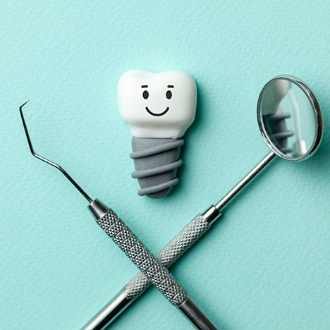 Dental instruments crossed below dental implant with face