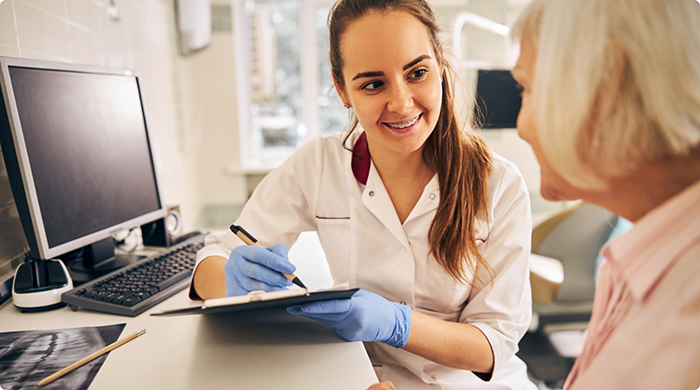 Dental team member sitting next to computer and filling out information for patient