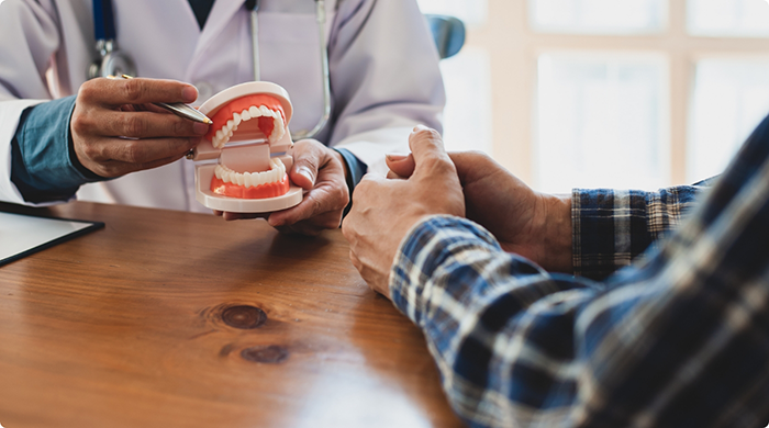 Dentist showing patient model of dentures in Lancaster