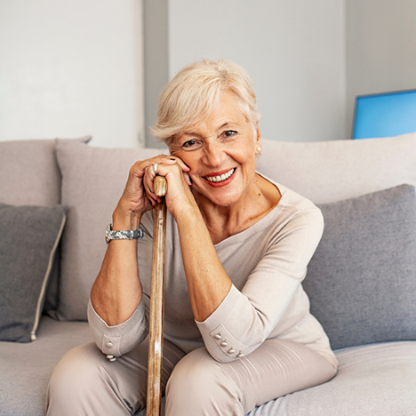 Woman with walking stick sitting on couch
