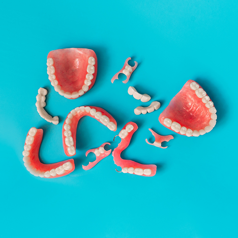 Multiple full and partial dentures scattered on blue surface