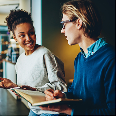 Woman in grey shirt talking to man with glasses