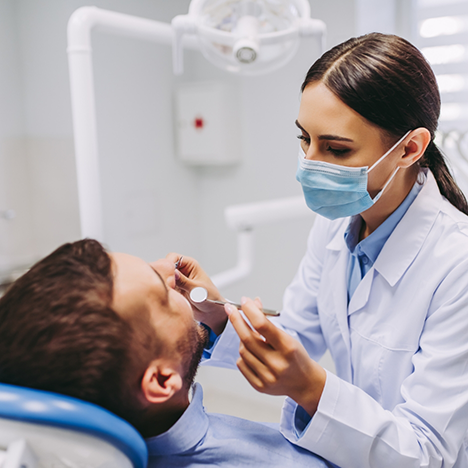Female dentist examining male patient's mouth