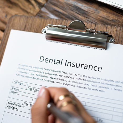 Filling out dental insurance form on clipboard