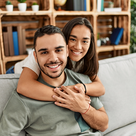 Man sitting on couch hugged from behind by woman