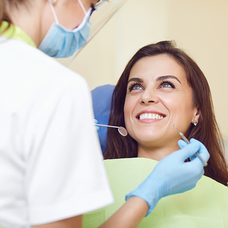 Woman smiling up at dentist examining her teeth