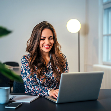 Woman with long brown hair typing on her laptop