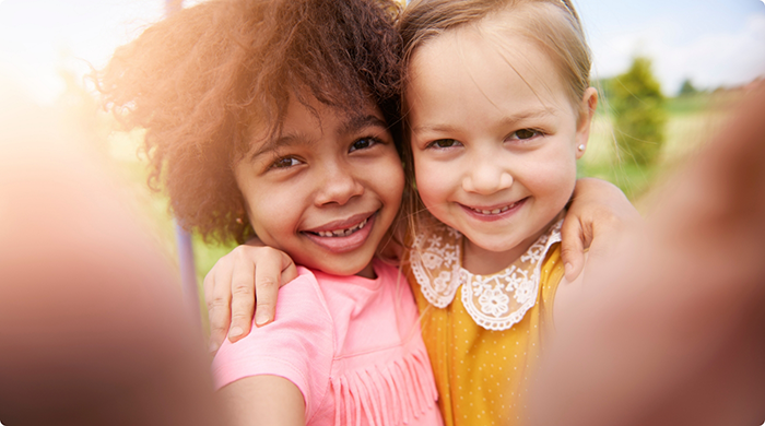Close-up of two kids smiling outside
