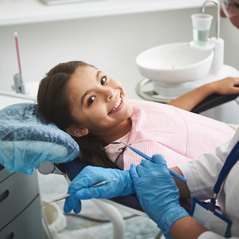 Little girl in dental chair looking up and smiling