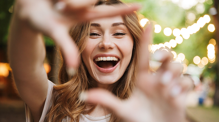 Woman framing her smile with her fingers