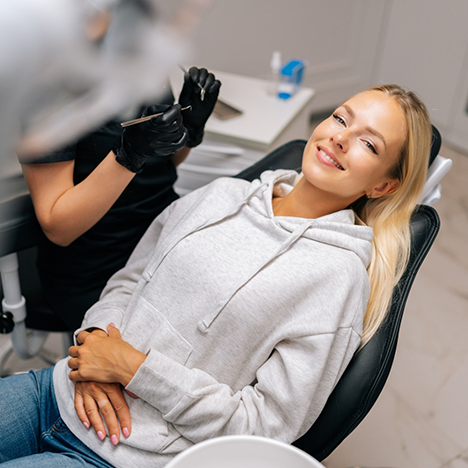 Woman in hoodie sitting back in dental chair