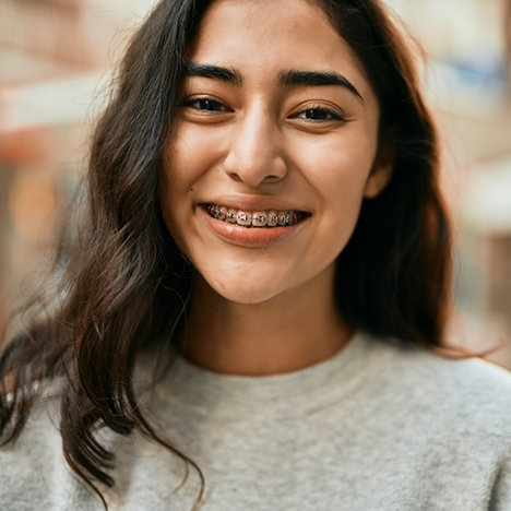 Woman in grey shirt smiling with braces
