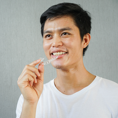 Man in white shirt taking clear aligner out of mouth