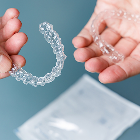 Close-up of two hands holding SureSmile clear aligners