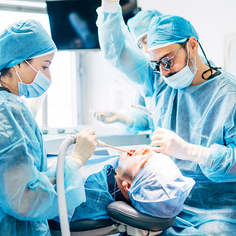 Dental team in masks performing dental implant surgery