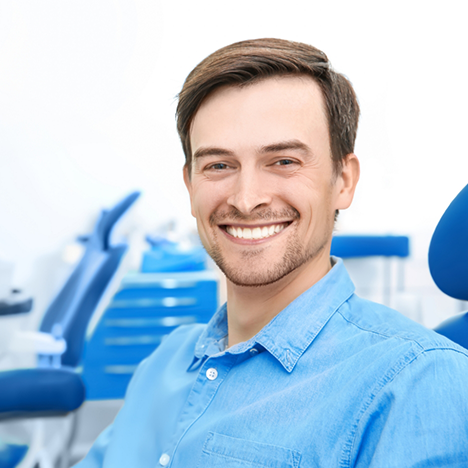 Man in button-up blue shirt smiling in dental chair