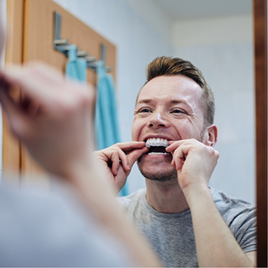 Man putting in tray for take-home teeth whitening