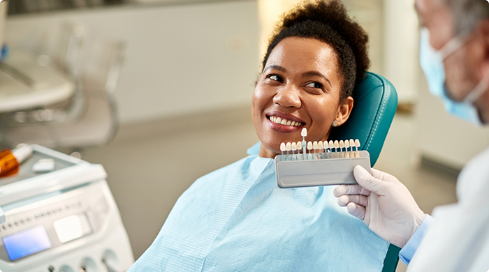 Woman smiling while teeth are being shade matched for veneers in Lancaster