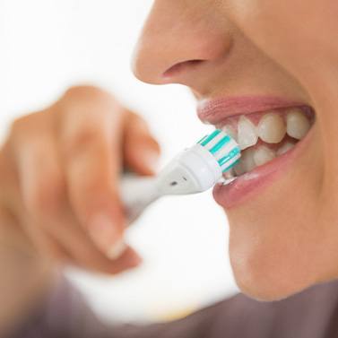 A woman brushing her teeth in front of a bathroom mirror