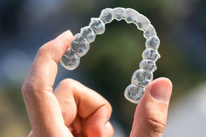 Someone holding an Invisalign aligner