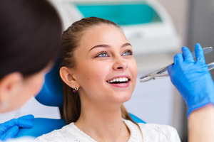 Smiling female dental patient about to have tooth extracted